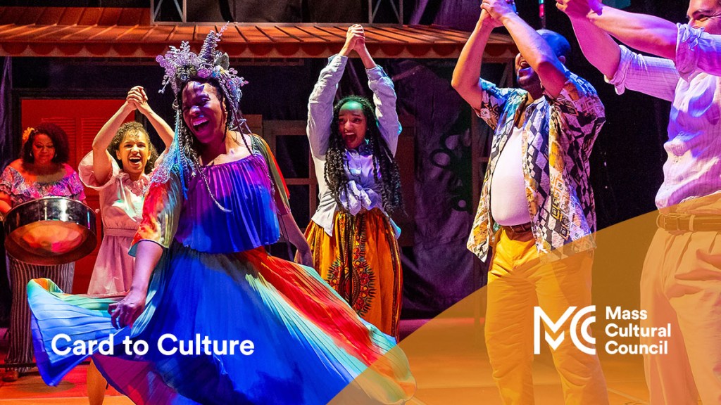 Performance still with a woman twirling in a blue dress surrounded by 6 other actors with their hands clasped together and raised over their heads cheering her on as part of a SpeakEasy Stage Company production